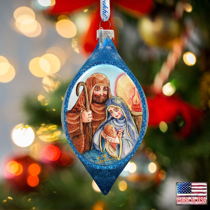 Decorative Christmas ornament with a nativity scene on a blurred Christmas tree background.